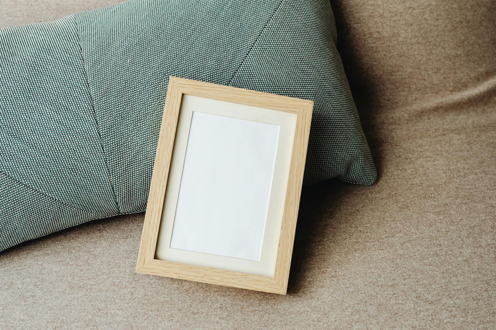 Minimalist image of a wooden frame and textured pillow on a sofa, ideal for mockups.